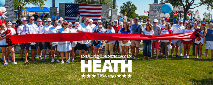 Community members gather for a ribbon-cutting ceremony celebrating the newly renovated Towne Center Park in Heath, Texas, during the city's Independence Day festivities. A large American flag hangs in the background as officials and residents stand behind a wide red ribbon, with patriotic decorations, balloons, and cheerleaders on either side. The image includes the text: "Independence Day in Heath – USA 250.