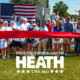 Community members gather for a ribbon-cutting ceremony celebrating the newly renovated Towne Center Park in Heath, Texas, during the city's Independence Day festivities. A large American flag hangs in the background as officials and residents stand behind a wide red ribbon, with patriotic decorations, balloons, and cheerleaders on either side. The image includes the text: "Independence Day in Heath – USA 250.