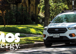 A white SUV driving in a suburban neighborhood with an Atmos Energy logo on the side of the vehicle.