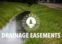 A drainage ditch with grass slopes, full of rain water.
