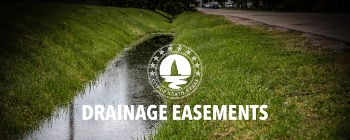 DrainageEasements A drainage ditch with grass slopes, full of rain water.