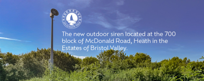 The new outdoor siren located at the 700 block of McDonald Road in Heath, surrounded by trees under a clear blue sky.