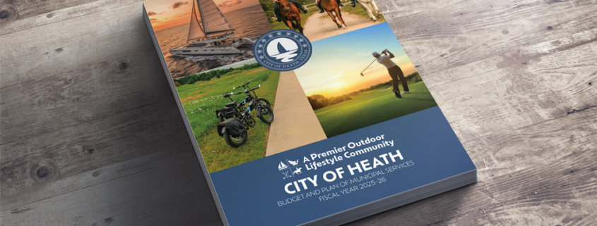 Stack of FY2025-2026 Budget documents on a wooden table.